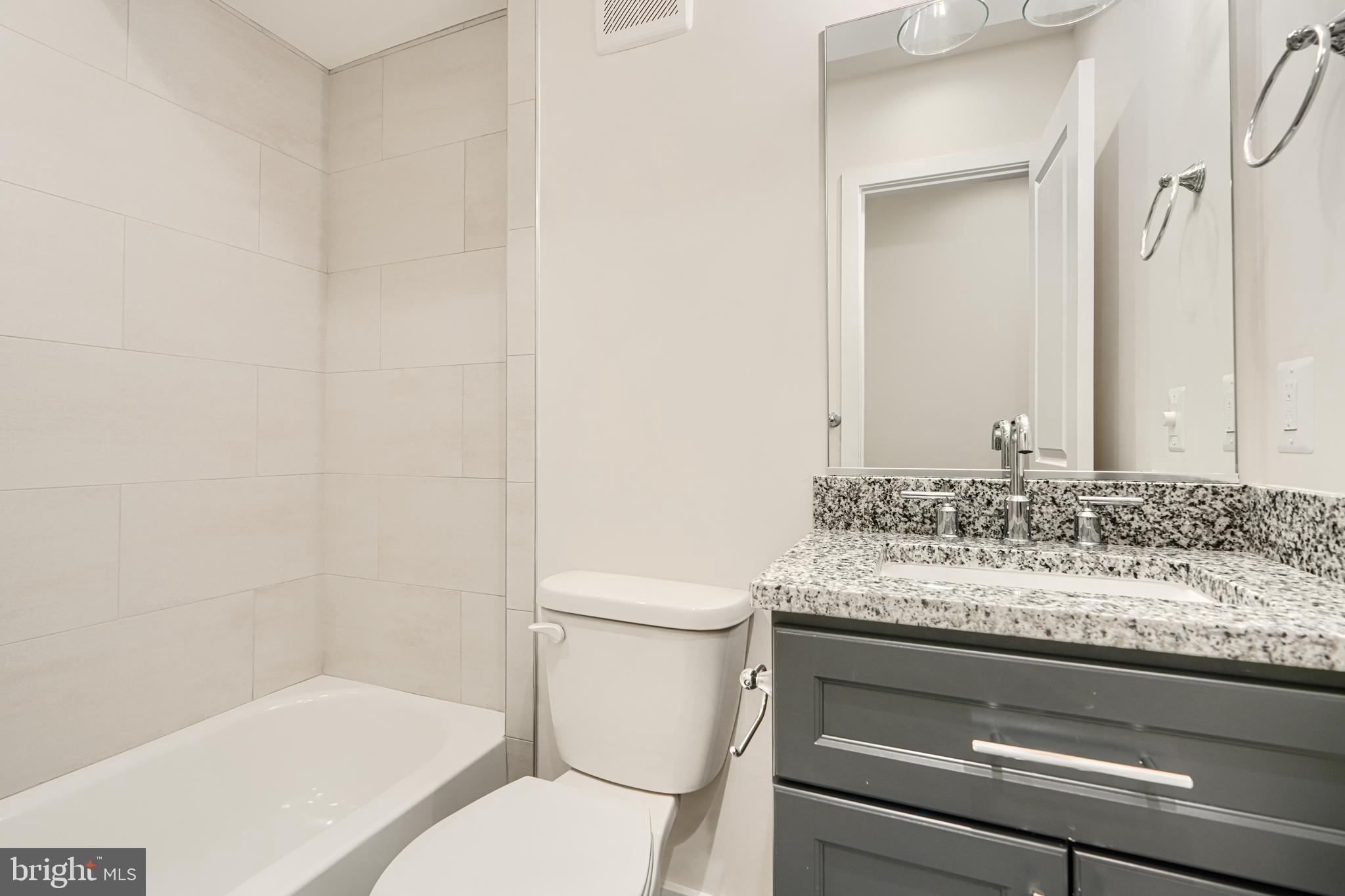 719 South Robinson Street Baltimore, MD 21224 - Photo 17 of 31 a bathroom with a granite countertop toilet sink and mirror