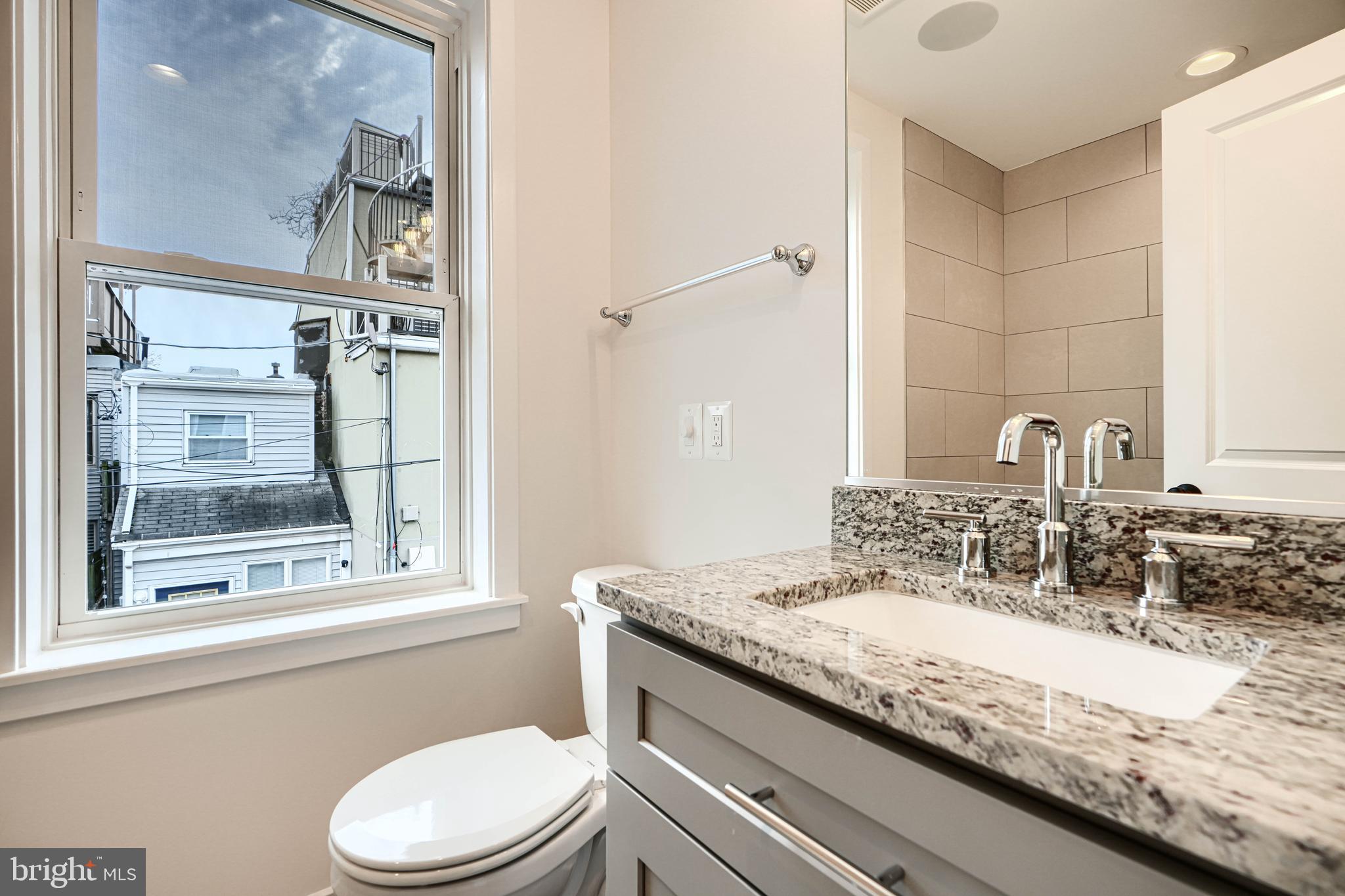 719 South Robinson Street Baltimore, MD 21224 - Photo 21 of 31 a bathroom with a granite countertop sink a toilet and a mirror