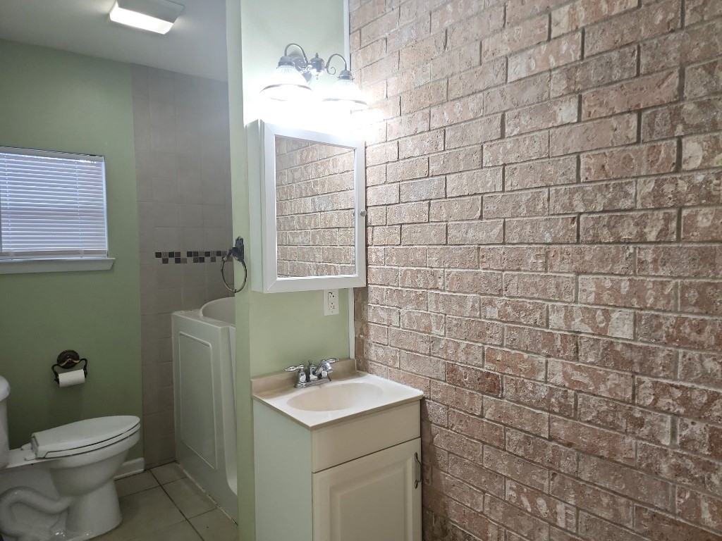 807 Country Club Road Georgetown, TX 78628 - Photo 19 of 31 Bathroom featuring vanity, light tile patterned flooring, and brick wall