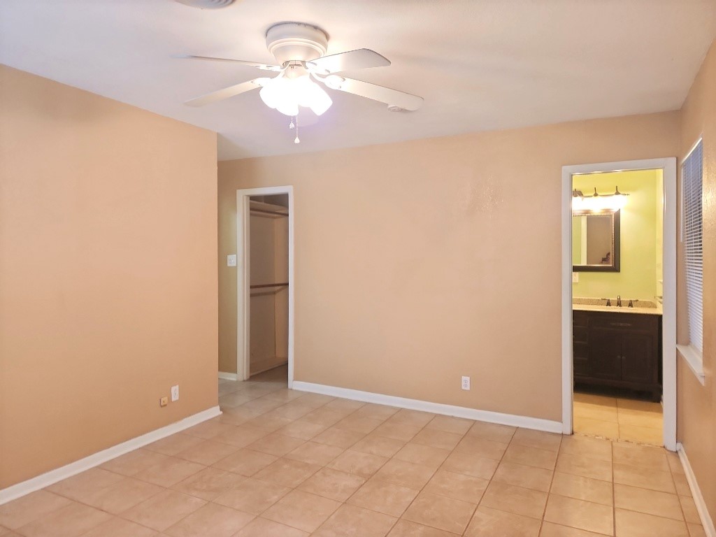 807 Country Club Road Georgetown, TX 78628 - Photo 23 of 31 Unfurnished bedroom featuring ceiling fan, light tile patterned floors, connected bathroom, and a spacious closet