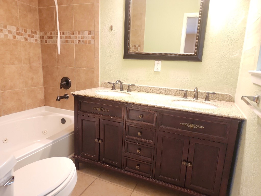 807 Country Club Road Georgetown, TX 78628 - Photo 25 of 31 Full bath with a textured wall, double vanity, light tile patterned floors, and a combined bath / shower with jetted tub