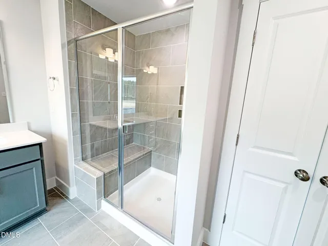 a spacious bathroom with a double vanity sink a large mirror and a shower