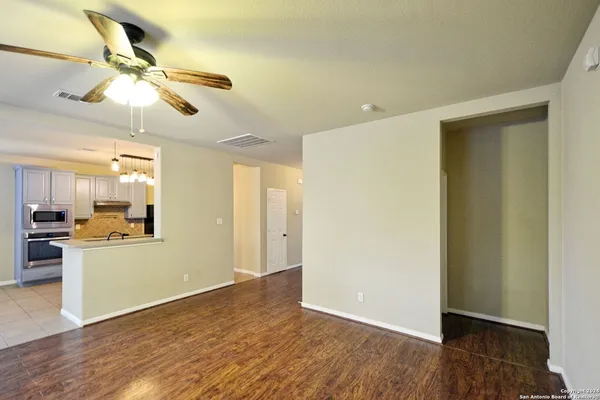 a view of a livingroom with a ceiling fan & kitchen space