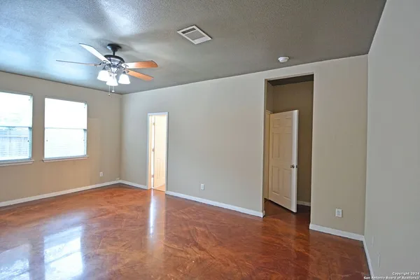 an empty room with windows and fan