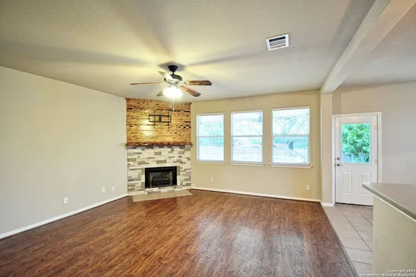 a view of an empty room with a window and wooden floor