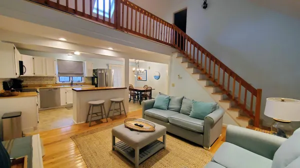 a living room with furniture kitchen view and a wooden floor
