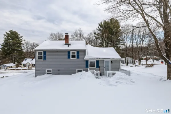 a view of a house with snow on the roadside