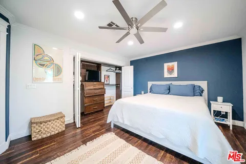 a spacious bedroom with a bed and a flat tv screen on dresser