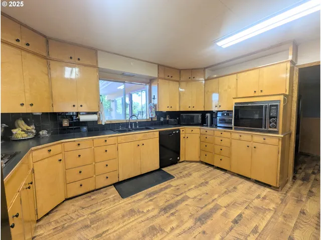 a large kitchen with stainless steel appliances double cabinets and a large window