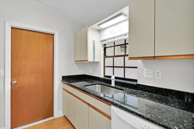 a kitchen with granite countertop white cabinets and sink