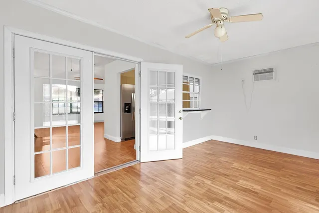 a view of an empty room with wooden floor and a window