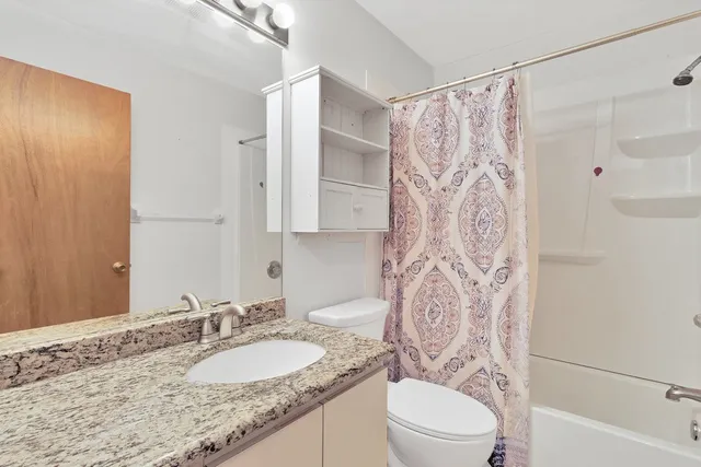a bathroom with a granite countertop sink toilet and shower