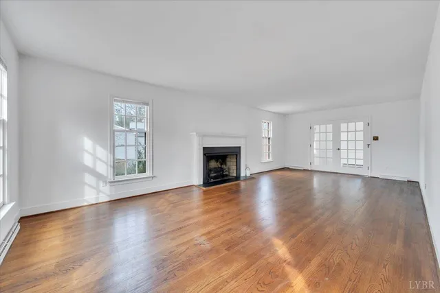a view of empty room with wooden floor and fireplace