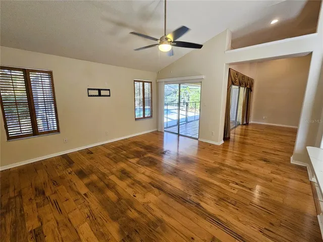 a view of an empty room with window and wooden floor