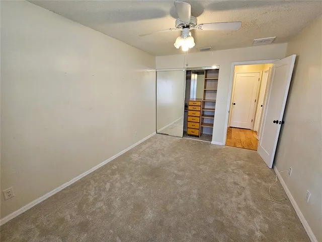 an empty room with closet and ceiling fan