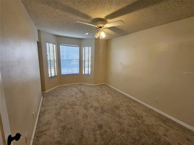 an empty room with windows and chandelier fan