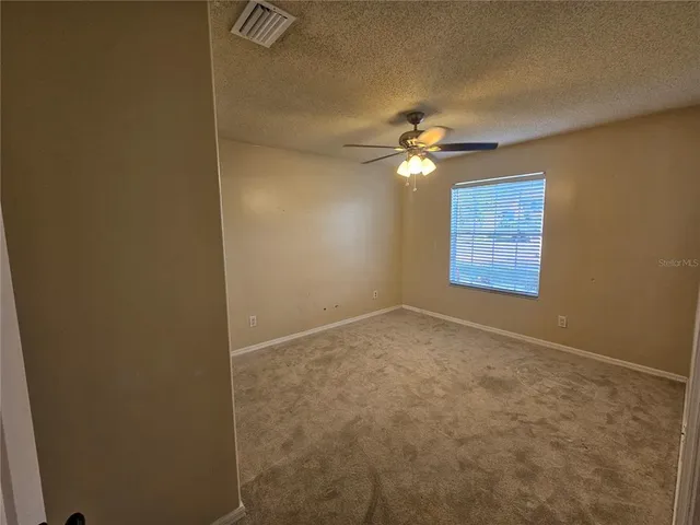 an empty room with windows and fan