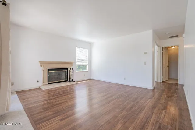 a view of empty room with wooden floor and fireplace