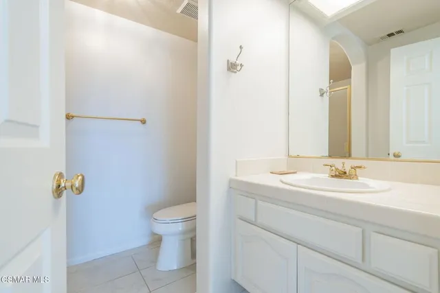 a bathroom with a granite countertop sink a toilet and a mirror