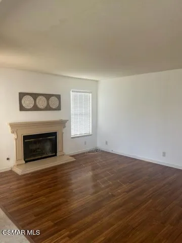 a view of empty room with wooden floor and fireplace