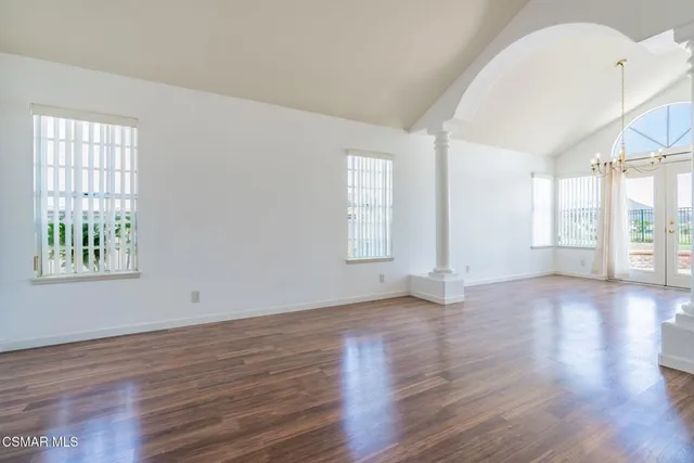 an empty room with wooden floor and windows