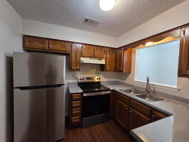 a view of a kitchen with a sink stove refrigerator and wooden floor