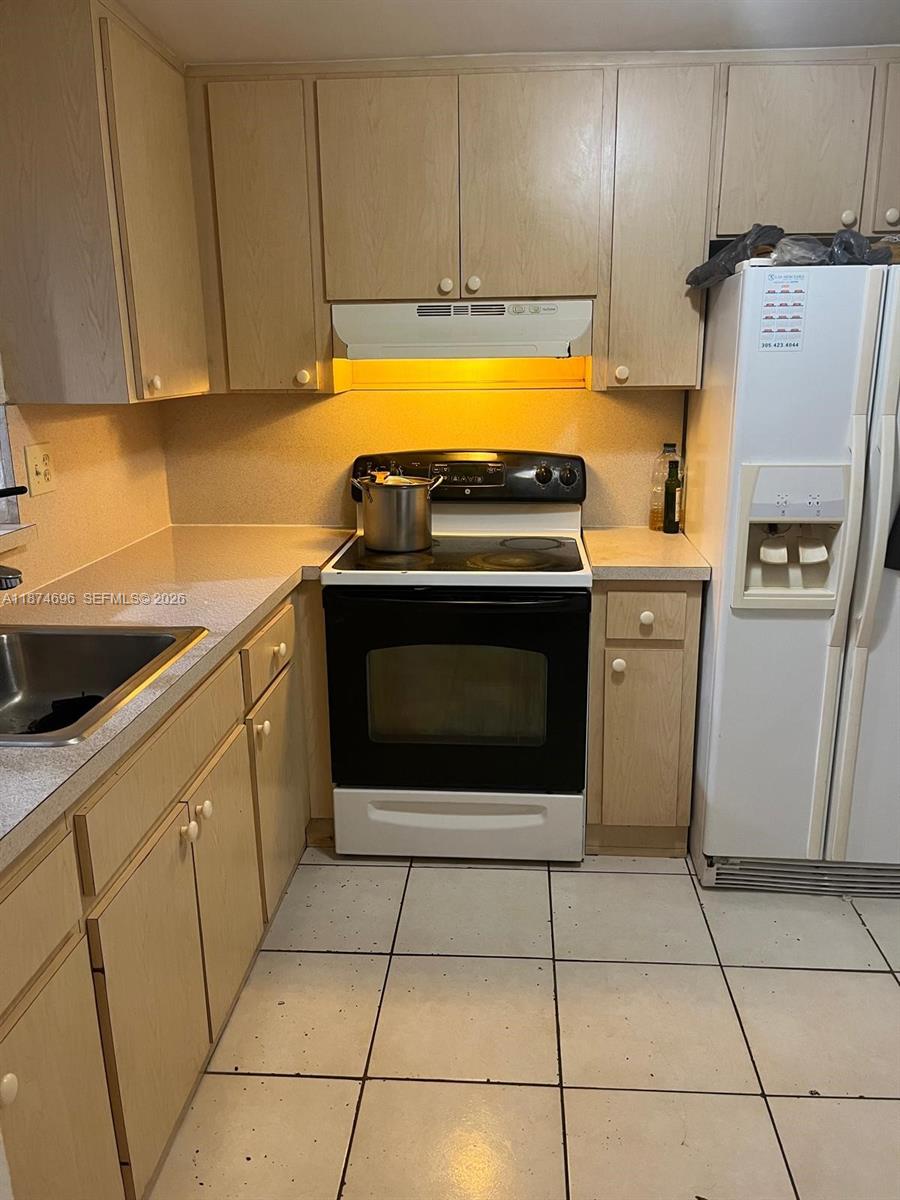 11295 Southwest 88th Street, Unit M109 Miami, FL 33176 - Photo 4 of 17 a kitchen with granite countertop a stove a sink and a refrigerator