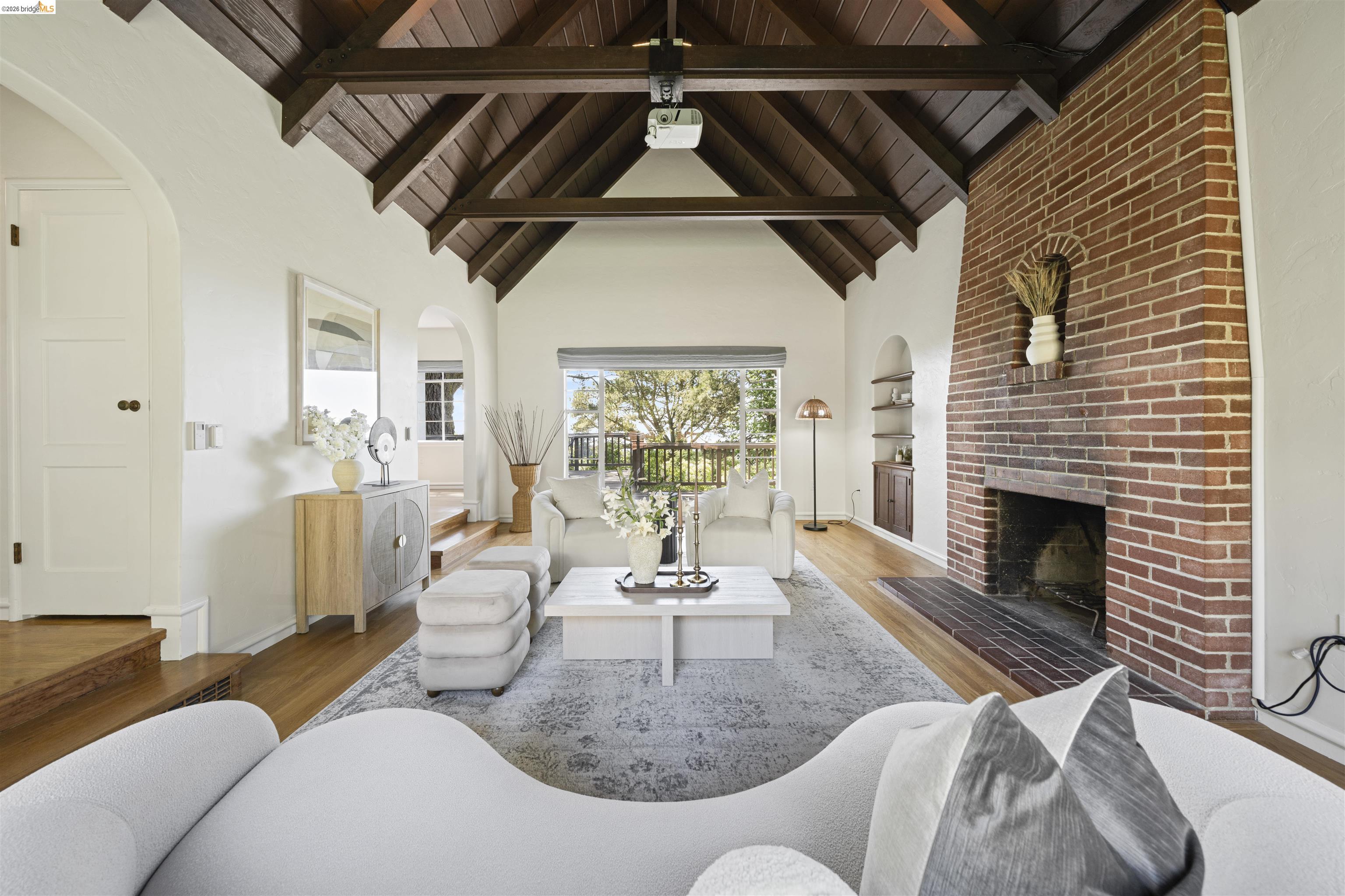 1170 Sterling Avenue Berkeley, CA 94708 - Photo 5 of 52 Living area with arched walkways, a brick fireplace, wood finished floors, and a high wood beamed ceiling