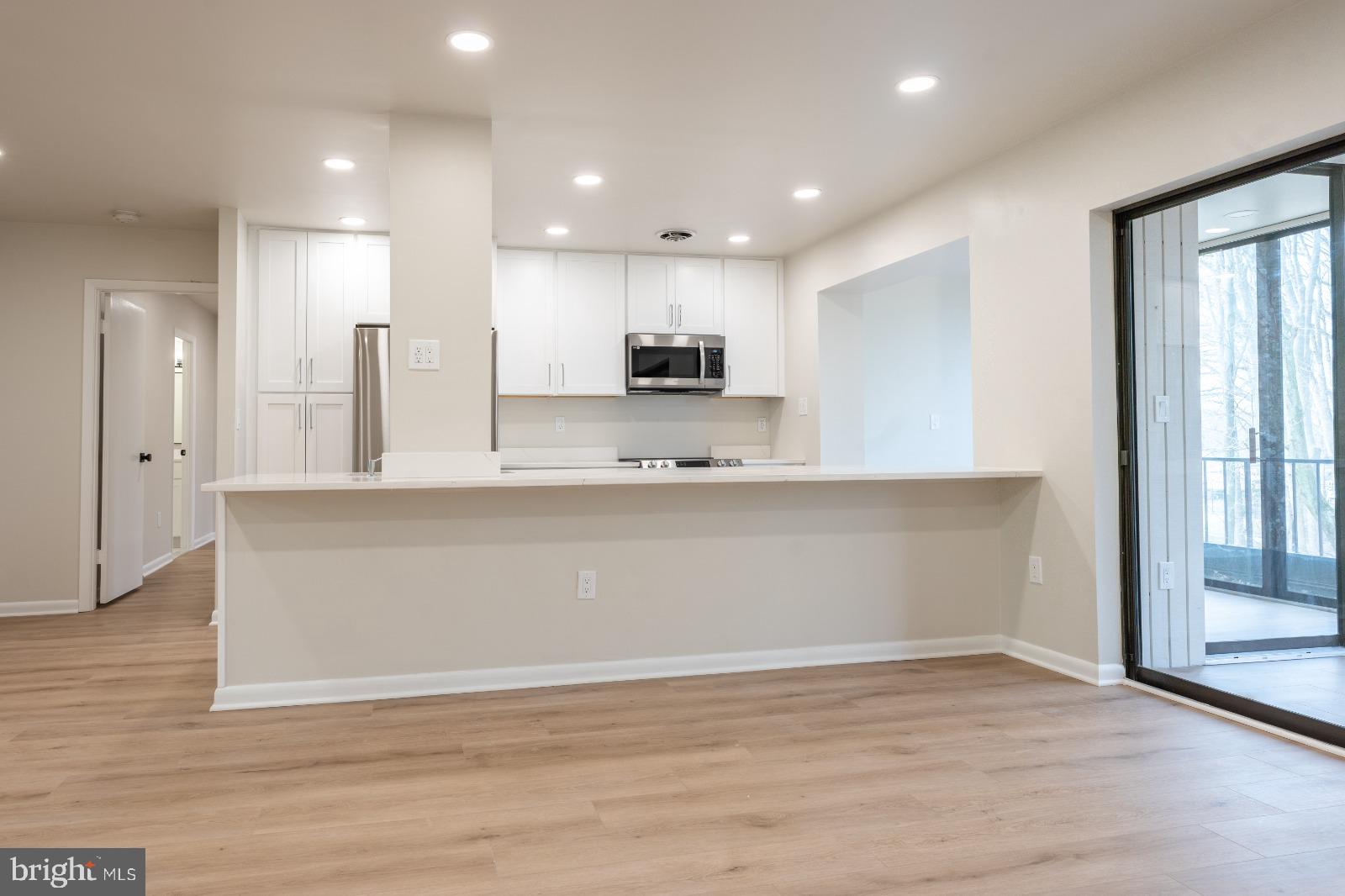 6350 Red Cedar Place, Unit 309 Baltimore, MD 21209 - Photo 13 of 29 a view of kitchen with kitchen island stainless steel appliances wooden floor cabinets and a window