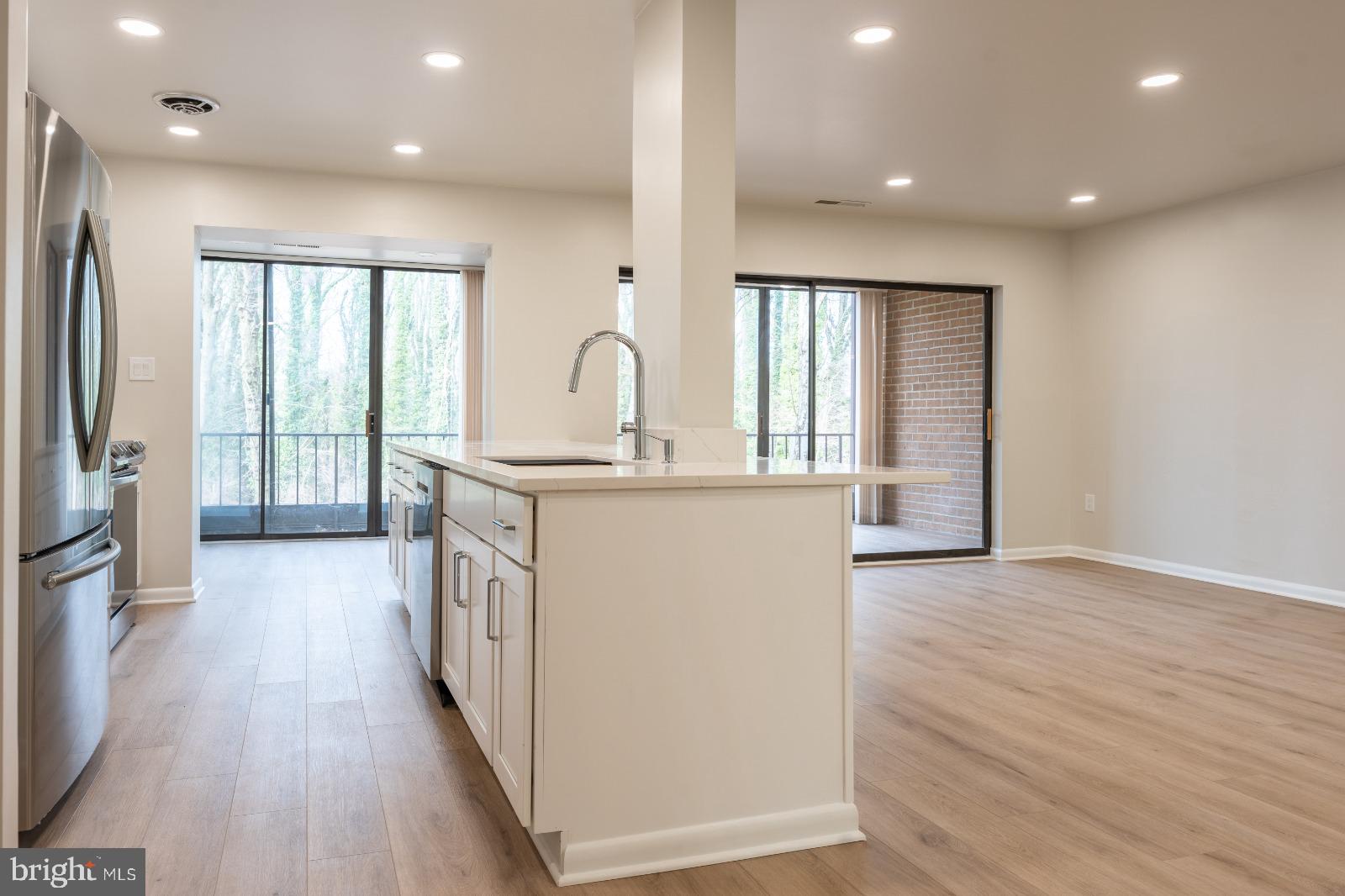 6350 Red Cedar Place, Unit 309 Baltimore, MD 21209 - Photo 8 of 29 a kitchen with stainless steel appliances granite countertop a refrigerator a sink and a stove with wooden floors