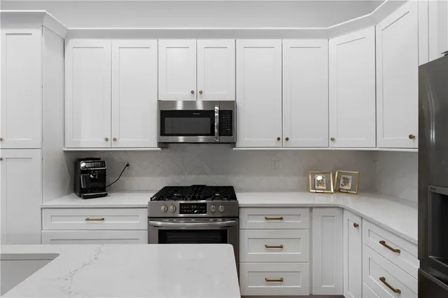 a kitchen with white cabinets and black appliances