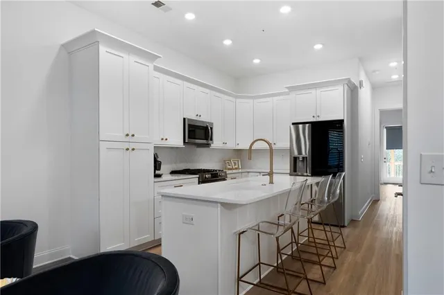 a kitchen with stainless steel appliances a stove a sink a microwave a refrigerator and cabinets