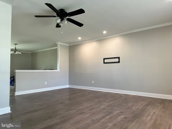 an empty room with wooden floor and fan