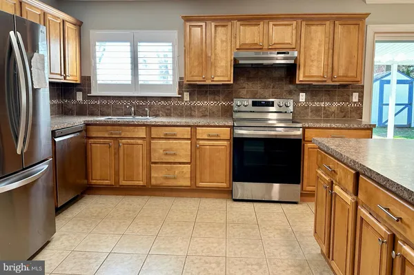 a kitchen with stainless steel appliances granite countertop a stove a sink and a refrigerator