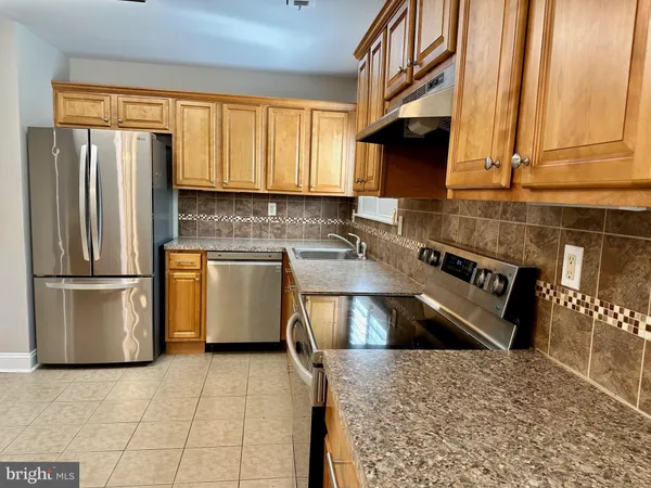 a kitchen with stainless steel appliances granite countertop a refrigerator a stove and a sink