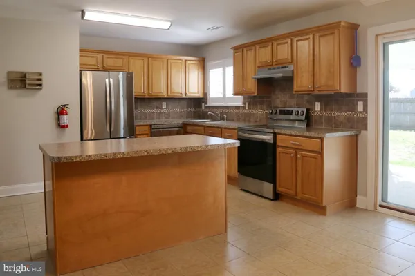 a kitchen with stainless steel appliances granite countertop a refrigerator a sink a stove and white cabinets