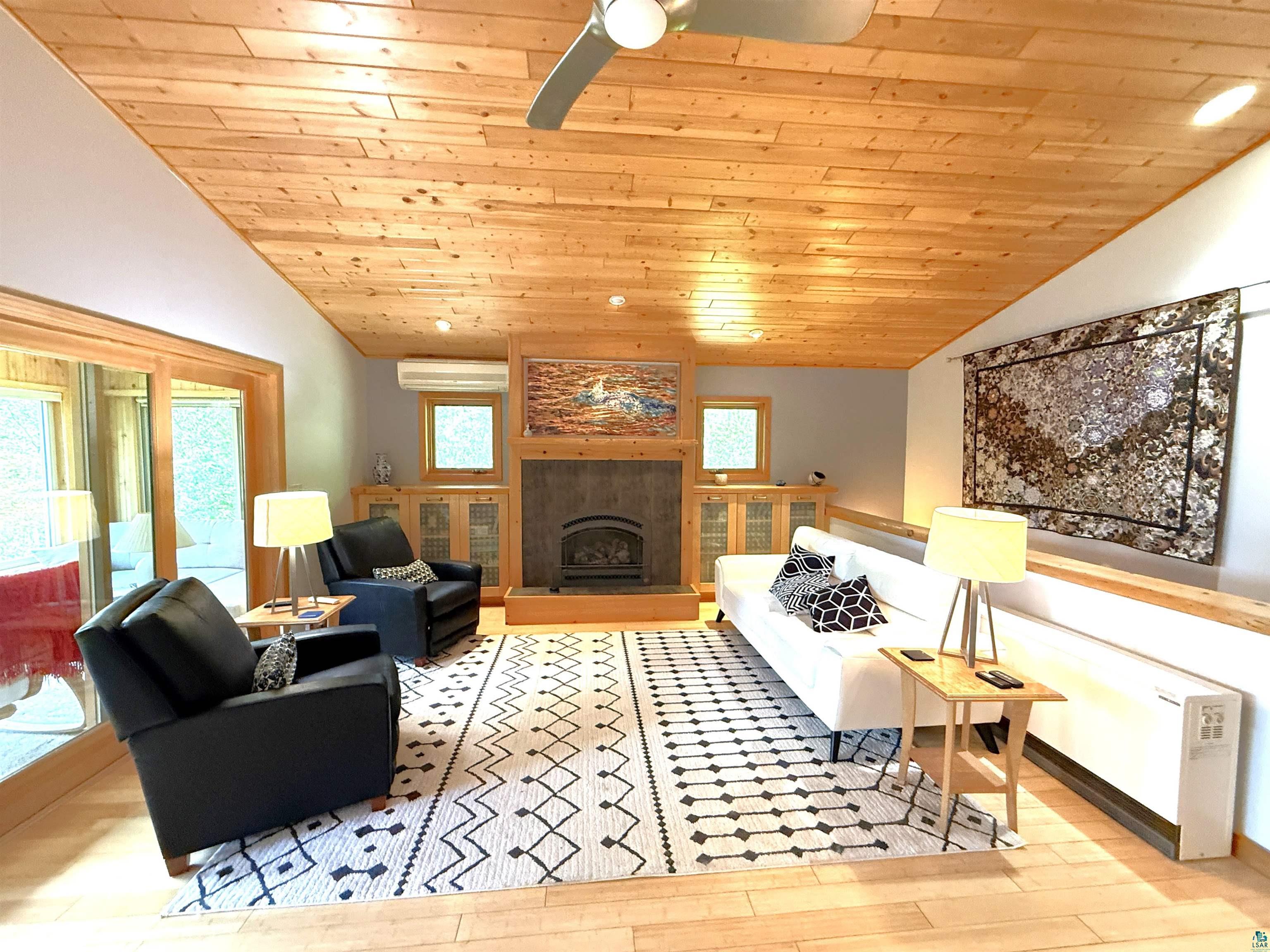 1787 North Bay Road Ely, MN 55731 - Photo 11 of 40 Living area featuring wood-finish flooring, a wood plank ceiling, and a central fireplace with stone surround