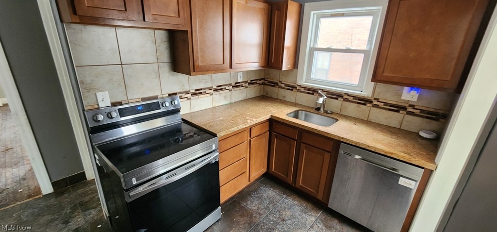 3599 Grosvenor Road Cleveland, OH 44118 - Photo 6 of 25 Kitchen featuring stainless steel appliances, wood finish cabinets, tasteful backsplash, stone tile flooring, and light stone counters