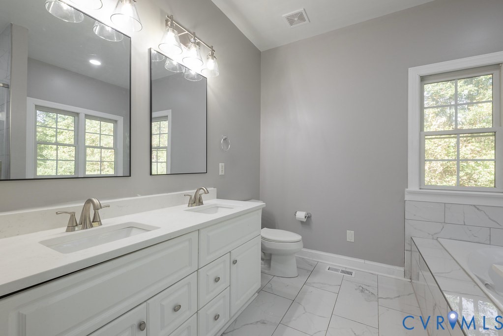 15438 West Patrick Henry Road Montpelier, VA 23192 - Photo 13 of 45 a bathroom with a double vanity sink a toilet and a mirror