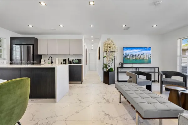 a living room with stainless steel appliances furniture a rug and a kitchen view