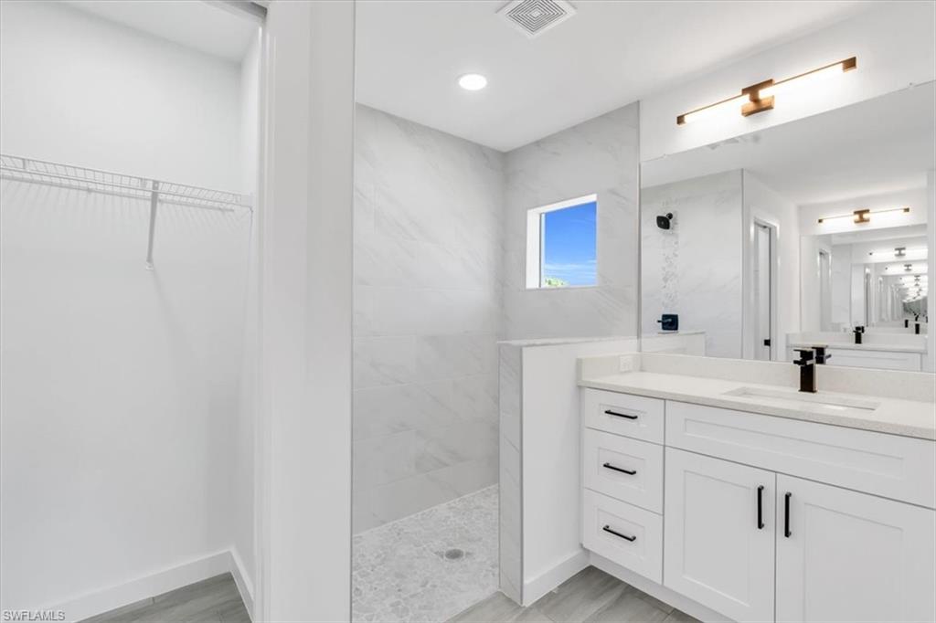 2812 15th Street Southwest Lehigh Acres, FL 33976 - Photo 6 of 13 a bathroom with a double vanity sink a mirror and shower