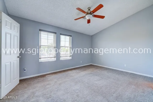 an empty room with windows and fan