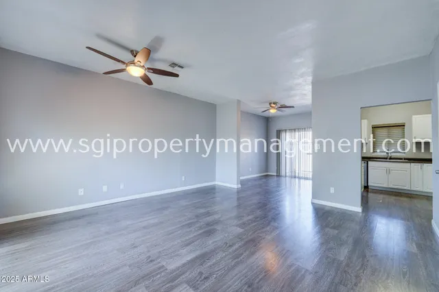 a view of a kitchen and an empty room with wooden floor
