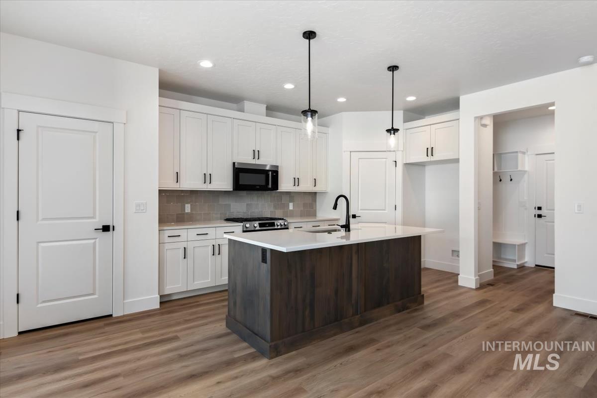 768 South Calhoun Lane Star, ID 83669 - Photo 10 of 36 Contemporary kitchen featuring white cabinetry, a large center island with a wood-finish base, stainless steel appliances, and wood-finish flooring