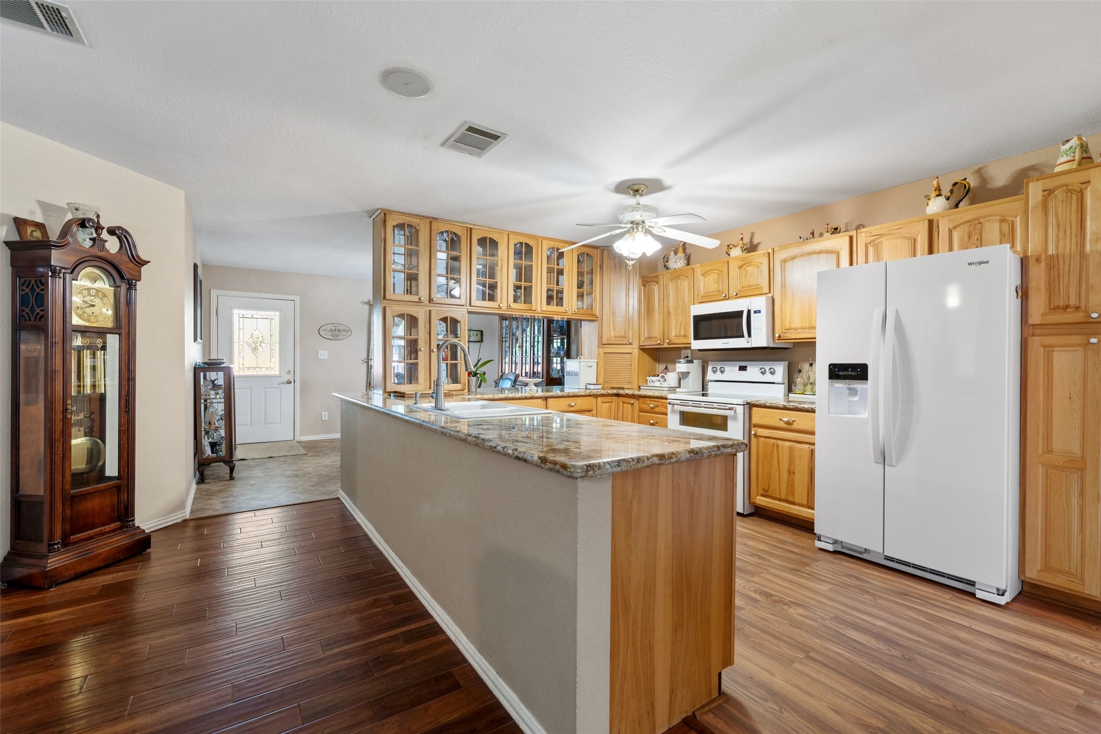 399 Upper Elgin River Road Elgin, TX 78621 - Photo 23 of 39 Kitchen featuring glass fronted cabinets, white appliances, light stone counters, light wood-like LVP flooring, and a ceiling fan