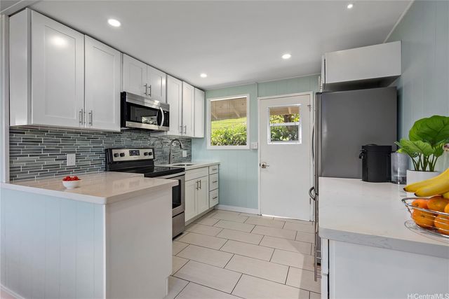 a kitchen with stainless steel appliances a stove a sink a microwave a refrigerator a counter top space and cabinets