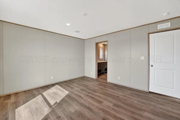 a view of an empty room with wooden floor and closet