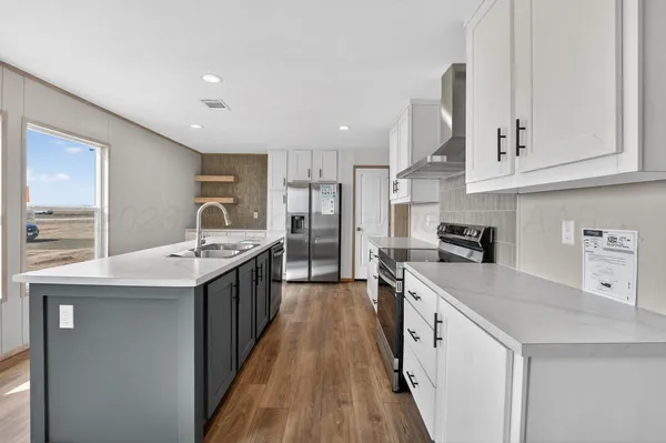a large kitchen with stainless steel appliances granite countertop a lot of counter space and wooden floor
