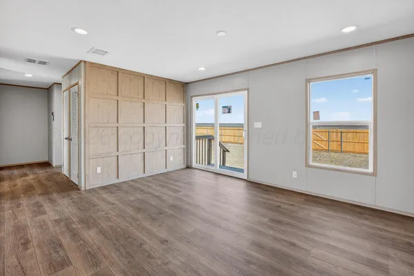 a view of an empty room with window and wooden floor