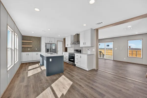 a large kitchen with kitchen island wooden floors and stainless steel appliances